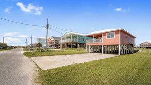 A residential area with houses on stilts, a paved road, and utility poles. - Coral Breeze (Fort Morgan)