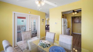 A dining area with a glass table, chairs, and a ceiling fan. - Coral Breeze (Fort Morgan)