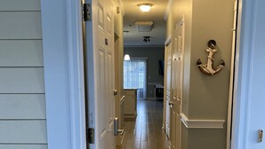 Un couloir doté d’un plancher en bois, de portes blanches et d’un paillasson sur lequel est inscrit le mot « Bienvenue ».