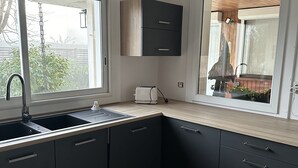 Una cocina moderna con armarios oscuros, un fregadero y una ventana con vistas a un jardín.
