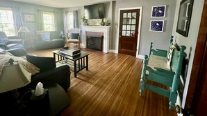 A living room with a fireplace, a television, and a green chair. - Convenient to every event that Louisville hosts! (Audubon Park)