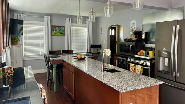 A modern kitchen with a granite countertop, stainless steel appliances, and pendant lighting. - Convenient to every event that Louisville hosts! (Audubon Park)