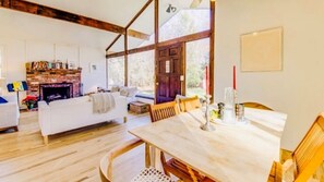 Cozy living area with a brick fireplace, wooden dining table, and large windows.
