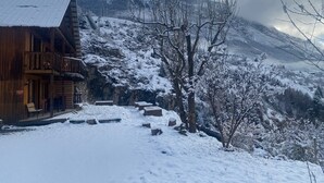 A wooden cabin with a balcony, a snow-covered landscape, and a mountain in the background.