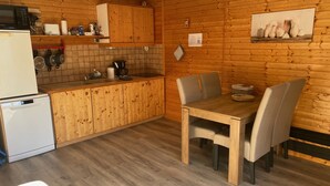 A kitchen with wooden cabinets, a dining table with chairs, a refrigerator, and a microwave.