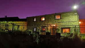 A stone building with a metal fence, a lit street lamp, and a number '51' sign. - Casa Rural de Alquiler Completo (Ligos)