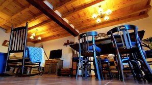 A rustic wooden interior with exposed beams, a chandelier, and multiple chairs. - Casa Rural de Alquiler Completo (Ligos)