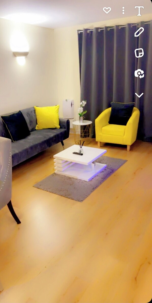 Una sala moderna con un sofá gris, un sillón amarillo y una mesa de centro blanca.