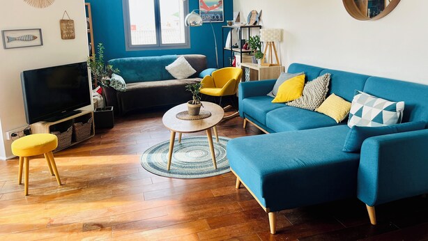A living room with a blue sofa, yellow chair, and a TV. - Loft 80m2 top floor 100m beach & center Bandol (Bandol)