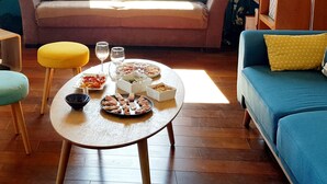 A cozy living room with a sofa, a coffee table with food and drinks, and a window with blinds. - Loft 80m2 top floor 100m beach & center Bandol (Bandol)