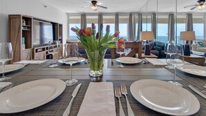 Et spisebord dækket til fire med tulipaner, en sofa og udsigt til havet.