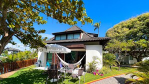 A two-story house with a tiled roof, a hammock, outdoor furniture, and a paved driveway. - Beach Class Muro Alto - Bangalô com Vista Para Piscina e mar (Ipojuca)
