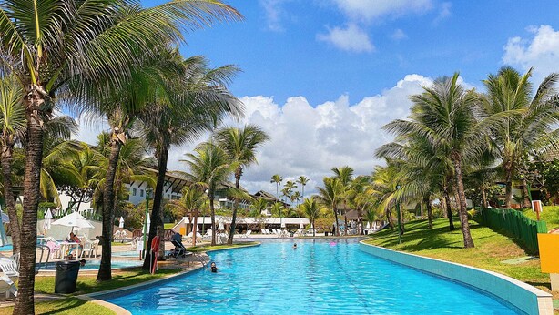 A swimming pool surrounded by palm trees and a clear blue sky. - Beach Class Muro Alto - Bangalô com Vista Para Piscina e mar (Ipojuca)