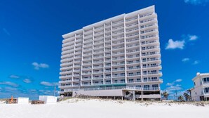 Ett hotell med flera våningar och balkonger, beläget på en sandstrand.