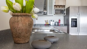 A kitchen with a stone vase containing white tulips, a stainless steel sink, and a microwave. - Villa Ocean - Indulge Yourself in Paradise (Indigo Bay)