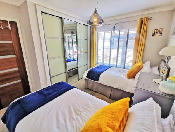 A hotel room with two beds, a sliding glass door, a bedside table with a lamp, and a view of the city through large windows. - Contemporary retreat with fantastic views, hot tub and large garden (Narberth)