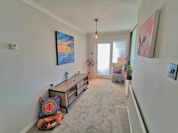 A hallway with a wooden bench, a fan, and a door leading to a balcony. - Contemporary retreat with fantastic views, hot tub and large garden (Narberth)