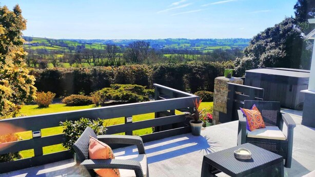 A terrace with wicker furniture and a view of green fields. - Contemporary retreat with fantastic views, hot tub and large garden  (Narberth)