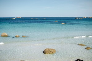 A beach with clear turquoise water and several large rocks in the sand. - Just a stone's throw from the beaches, a house with a large fenced-in yard (Cléder)