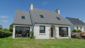 A modern house with a large glass door, a stone archway, and a small garden. - A stone's throw from the beaches, house with large enclosed garden (Cléder)