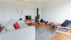 A modern living room with a sofa, armchair, coffee table, and a fireplace. - A stone's throw from the beaches, house with large enclosed garden (Cléder)