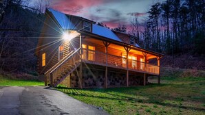 Una baita di legno con un portico, una scala e vista sulla foresta circostante.