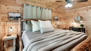 Una stanza accogliente in legno con un letto, una scrivania e una ventola a soffitto.