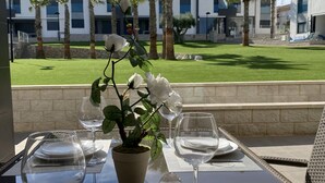 A dining table set with plates, glasses, and a potted plant. - OASIS BEACH apartments (Torrevieja)