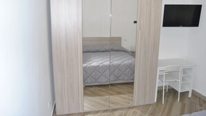 A bedroom with a bed, a desk, and a TV on the wall. - Agrigento center, fully furnished one-bedroom apartments 41 BDX (Agrigento)