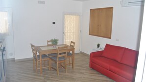 A room with a dining table, chairs, a red sofa, and an air conditioning unit. - Agrigento center, fully furnished one-bedroom apartments 41 BDX (Agrigento)