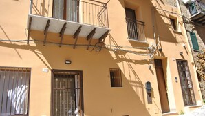 A multi-story building with balconies, barred windows, and a stone-paved ground. - Agrigento center, fully furnished one-bedroom apartments 41 BDX (Agrigento)