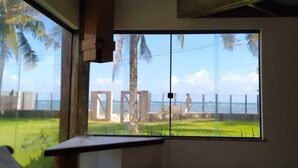 Una stanza con un'ampia porta-finestra scorrevole che dà su un balcone con vista sul mare e palme.