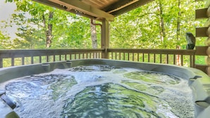 Ein Whirlpool mit Holzterrasse und Blick auf einen Wald.