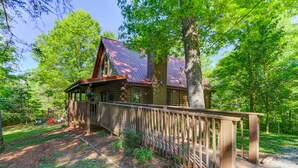 Eine Blockhütte mit Metalldach, umgeben von Bäumen und einer Holzterrasse.