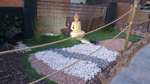 En trädgård med en Buddha-staty, en hängbro och en mur av tegelstenar.