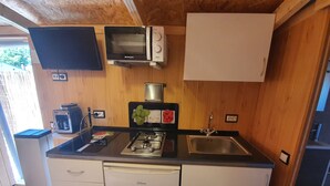 Ett kompakt kök med mikrovågsugn, spis, diskho och ett litet kylskåp.