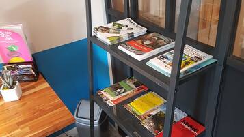 A metal bookshelf with travel books and a small table with a potted plant.