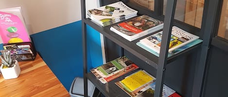 A metal bookshelf with travel books and a small table with a potted plant.