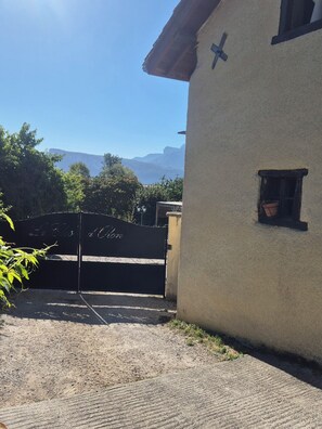 Ein Gebäude mit einer strukturierten Außenwand, einem kleinen Fenster und einem schmiedeeisernen Tor mit Verzierungen.