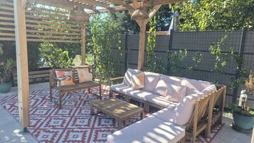 An outdoor patio with a wooden pergola, cushioned seating, and patterned rugs.