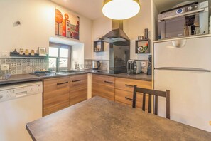 A modern kitchen with wooden cabinets, a stainless steel range hood, and a built-in dishwasher. - Gîte le Clos D'olon swimming pool & moutain view (Charnècles)