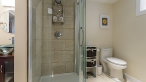 A modern bathroom with a glass-enclosed shower, a toilet, and a sink. - Basement Suite on Osborne (Winnipeg)