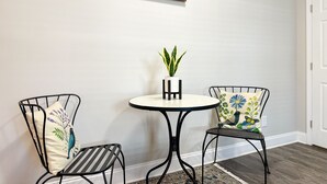 A small room with two metal chairs, a round table, a potted plant, and a sign above the table. - Downtown Greenville, SC Southern Simplicity! (Greenville)