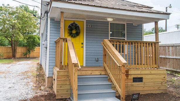 A small, single-story house with a yellow door, wooden steps, and a porch. - Downtown Greenville, SC Southern Simplicity! (Greenville)