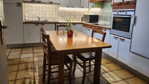 A kitchen with a wooden table, chairs, cabinets, and a microwave. - Louise's house (Fontenay-le-Comte)