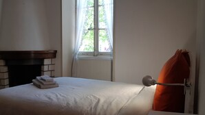 A bedroom with a bed, a fireplace, a window, and a radiator. - Louise's house (Fontenay-le-Comte)