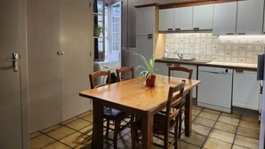A compact kitchen with a dining area, a washing machine, and a potted plant. - Louise's house (Fontenay-le-Comte)