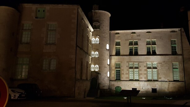 A historic building with illuminated windows and a central tower. - Louise's house (Fontenay-le-Comte)