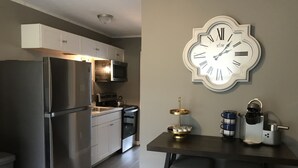 A modern kitchen with stainless steel appliances, a clock, and a coffee machine. - Cozy Court Street #2 (Fayetteville)