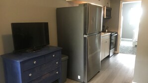 A kitchen with a stainless steel refrigerator, a blue dresser, and a flat-screen TV. - Cozy Court Street #2 (Fayetteville)